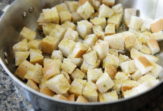 1. Этап. Салат Цезарь легкий: 5. Нарежьте мелкими кубиками хлеб. Посолите и при желании поперчите немного. Добавьте пару ложек оливкового масла и перемешайте.