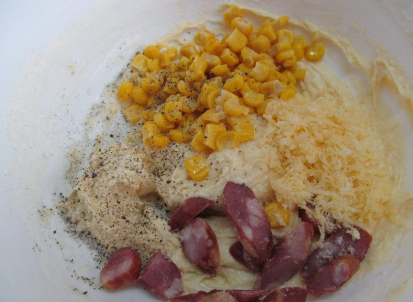 1. Этап. Закусочный кекс с кукурузой, колбасой и пармезаном: Добавить сыр, кукурузу и колбасу, поперчить и тщательно перемешать.