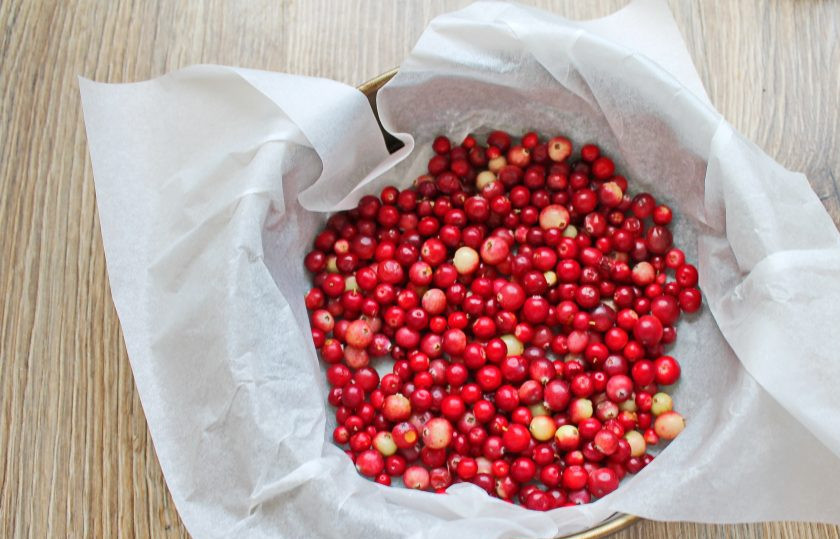 1. Этап. Бостонский клюквенный пирог: Форму для запекания диаметром 24 сантиметра застелите бумагой для выпечки. Насыпьте на дно сухую клюкву и разровняйте.