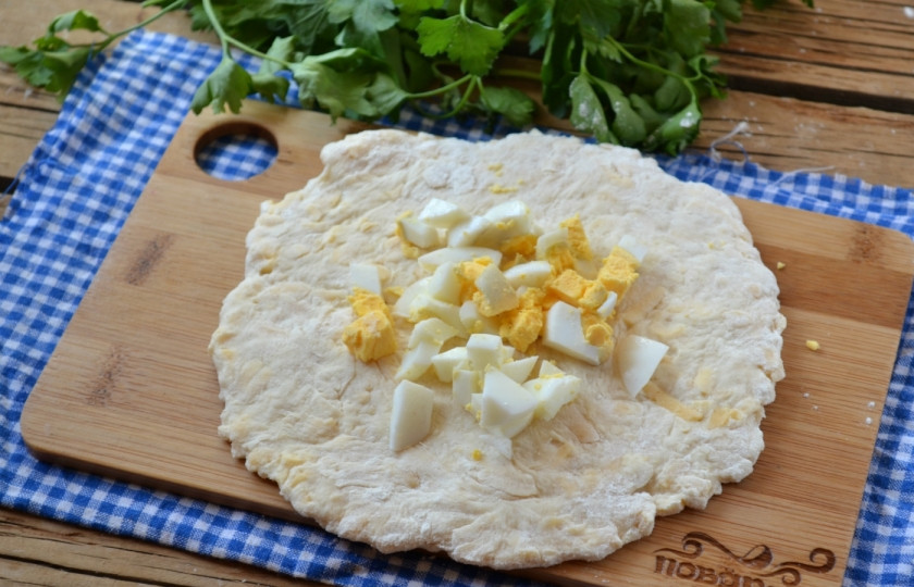 1. Этап. Сырные лепешки на кефире: Тесто разделите на 5 частей. Каждую часть раскатайте толщиной в 1 см. Сверху положите начинку из порезанного мелко яйца.