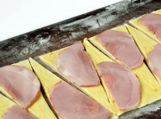 1. Этап. Круассаны с сыром и ветчиной: Ветчину нарезаем очень тонкими ломтиками и выкладываем на тесто.