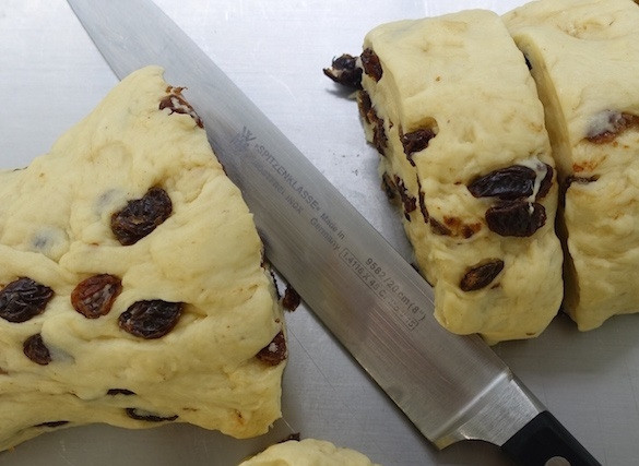 1. Этап. Булочки с изюмом в духовке: 6. Выложите тесто из миски и сформируйте рулет, затем нарежьте его небольшими кусочками.