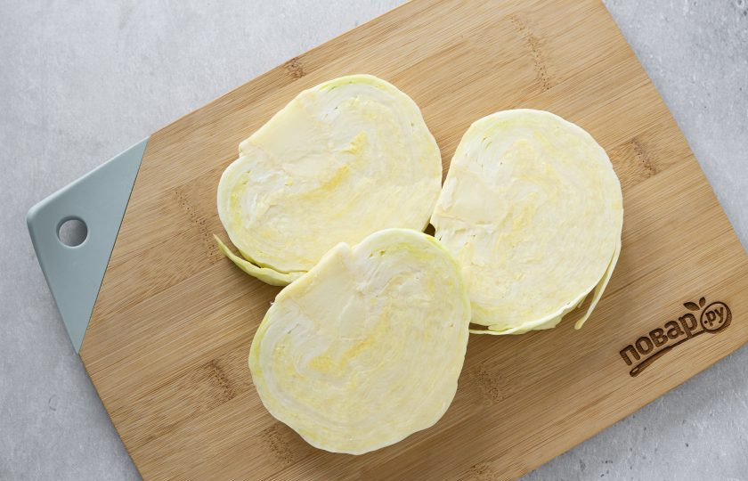 1. Этап. Стейки из капусты на сковороде: Капусту очистите от верхних плохих листьев. Нарежьте на несколько частей толщиной примерно 1,5 см., чтобы получились плоские стейки с кочерыжкой.