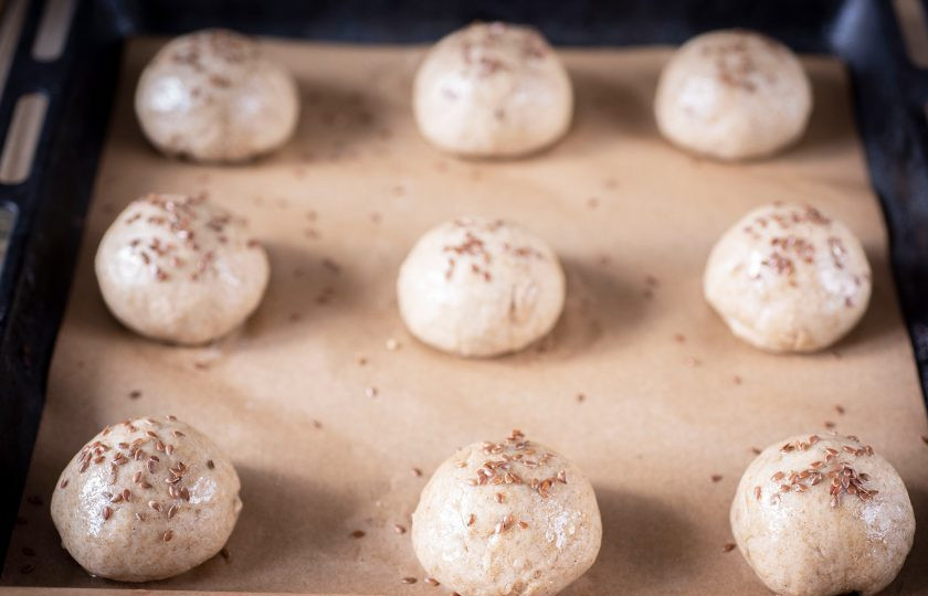 1. Этап. Булочки ржано-пшеничные: Отделяйте от общей массы теста небольшие кусочки весом примерно по 70-80 грамм, подкатайте каждый в шарик, выложите на противень, застеленный пергаментом для выпекания, смажьте поверхность каждого растительным маслом и присыпьте немного семенем льна. Выпекайте булочки в уже разогретой до 180 градусов духовке в течение 20-25 минут.