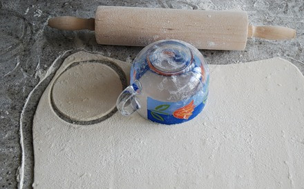 1. Этап. Пирожки с печенью и картошкой: Теперь выкладываем предварительно размороженное тесто на стол, посыпанный мукой, и раскатываем его тонко, при помощи чашки вырезаем из теста кружочки.