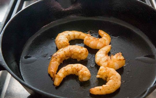 1. Этап. Закуска с креветками: 2. Разогрейте оливковое масло на сковороде, слейте маринад с креветок и выложите их на разогретую поверхность. Обжаривайте по 30 секунд с каждой стороны.