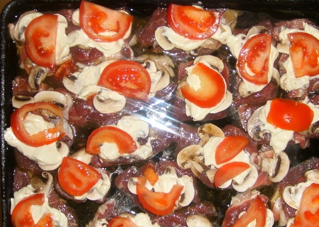 1. Этап. Говядина по-французски в духовке: Теперь выкладываем по кружочку помидора на каждый кусок мяса.