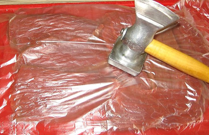 1. Этап. Рулеты из говядины в духовке: Для начала нам необходимо тщательно промыть говядину и высушить ее при помощи бумажных полотенец. Затем нарезаем мясо на кусочки шириной около 1 см поперек волокон, выкладываем их на разделочную доску, накрываем пищевой пленкой и отбиваем.
