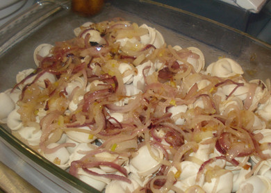 1. Этап. Пельмени, запеченные с сыром: 3. Форму для запекания немного смазать маслом. Положить на дно пельмени в один слой. Сверху выложить обжаренный лук, распределяя его по всей поверхности.