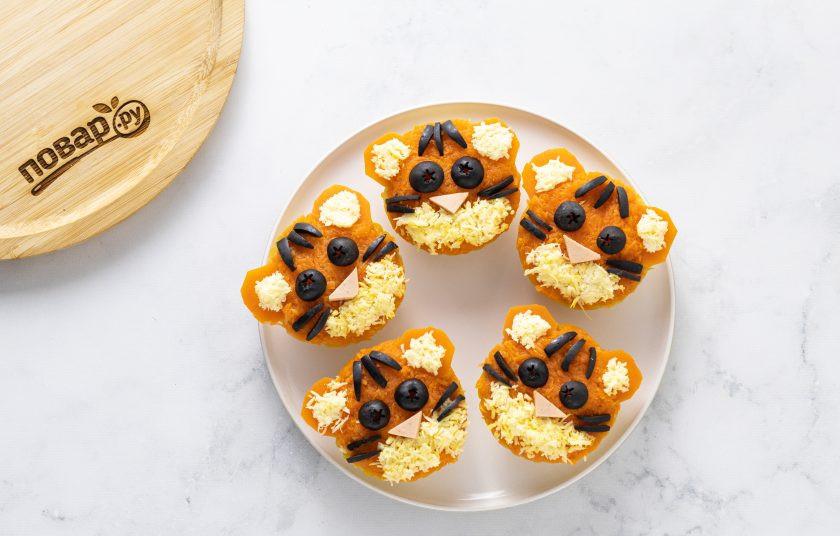 1. Этап. Тарталетки Тигрята: Для украшения сделайте из маслин глаза и полоски, из кусочка колбасы нос, а из мелко натертого сыра сформируйте ушки и нижнюю часть мордочек.