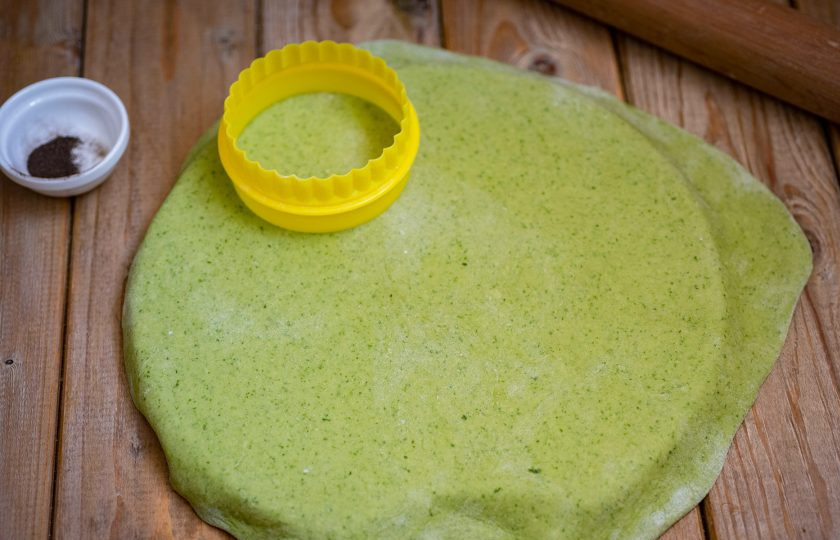 1. Этап. Зелёные пельмени со шпинатом: Охлажденное тесто раскатайте в пласт толщиной примерно в 1 мм. Круглой кондитерской вырубкой вырежете круги диаметром примерно в 7 см.