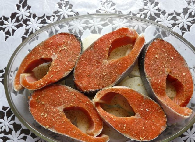 1. Этап. Горбуша в духовке под соусом: Сверху уложите рыбу. Посолите её, добавьте специи и перец.