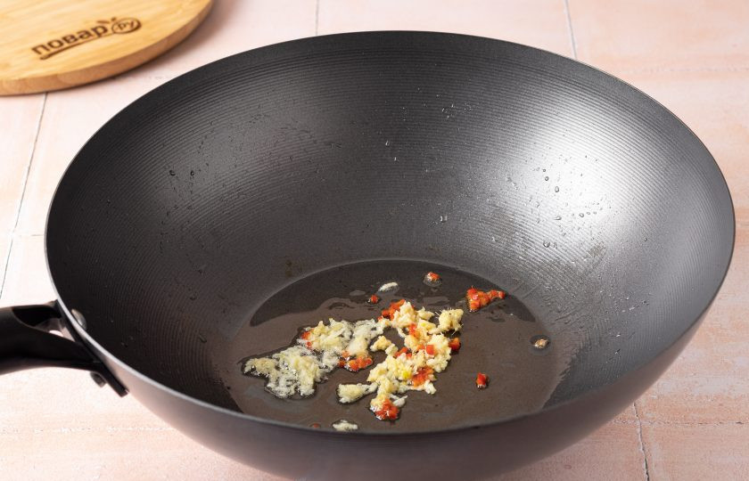 1. Этап. Соевое мясо в воке: Сковороду протрите и снова влейте 1/2 ст.л. растительного масла. Добавьте мелко порубленный корень имбиря, чеснок и перец чили. Обжаривайте их 30-40 секунд.