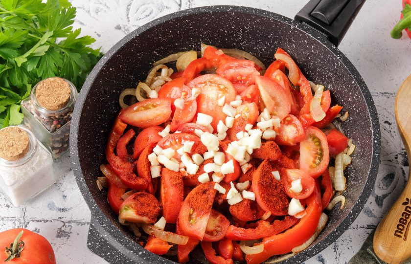 1. Этап. Мясо по-сербски: Затем добавьте нарезанные дольками помидоры, измельчённый чеснок и паприку.