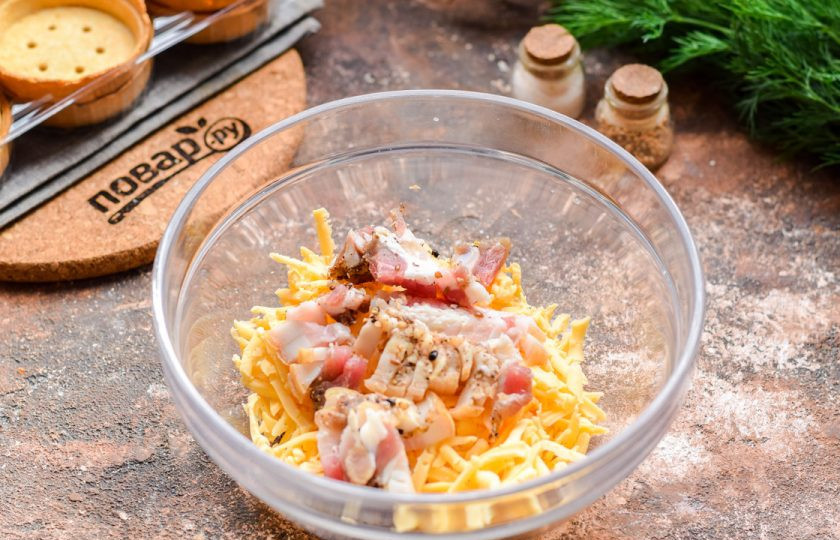 1. Этап. Тарталетки с беконом и сыром: Бекон нарежьте мелкими кубиками и переложите в сыр.