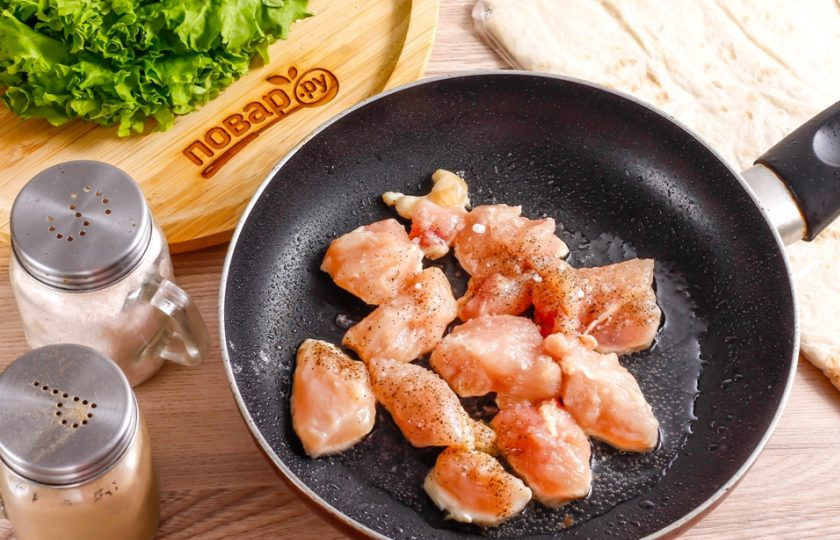 1. Этап. Курица в лаваше: Куриное филе промойте в воде и обсушите его бумажными салфетками. Можно использовать любую часть куриного мяса, например — срезанную с бедрышек или голеней. Срежьте жилы и пленки, нарежьте кубиками и выложите на сковороду, прогрев на ней растительное масло.