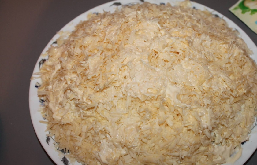 1. Этап. Салат Подсолнух с чипсами: Отварные яйца натрите на мелкой терке. Один желток отложите для украшения салата. Раскрошенными яйцами выкладываем следующий слой салата. Снова смазываем майонезом и присыпаем тертым сыром.