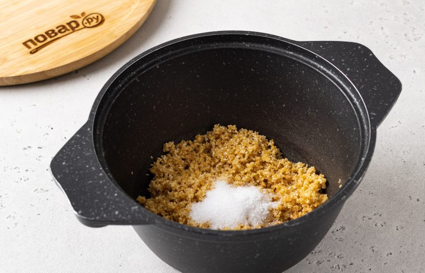 1. Этап. Пшеничная каша на воде: Переложите крупу в кастрюлю с толстым дном. Добавьте сахар и соль.