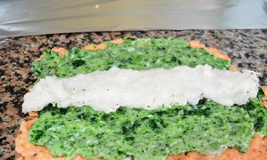 1. Этап. Рулет рыбный с нори: 2. На рабочий стол выложите лист пищевой пленки. Под пленку можно положить лист нори, чтобы угадать с размером рулета. Распределите ровным слоем на пленке филе красной рыбы, после выложите зеленую пасту и в центр — белую рыбу, как показано на фото.