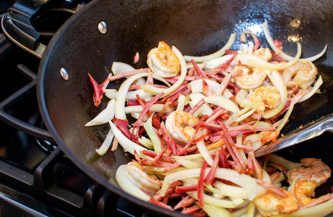 1. Этап. Лапша по-сингапурски: Нарезаем слайсами лук и бекон, засыпаем все на сковороду. Жарим 30 секунд и добавляем нарезанный таким же образом перец и морковь. Высыпаем горошек. Засыпаем карри и соль. Обжариваем до готовности овощей. Пересыпаем все к яйцам.