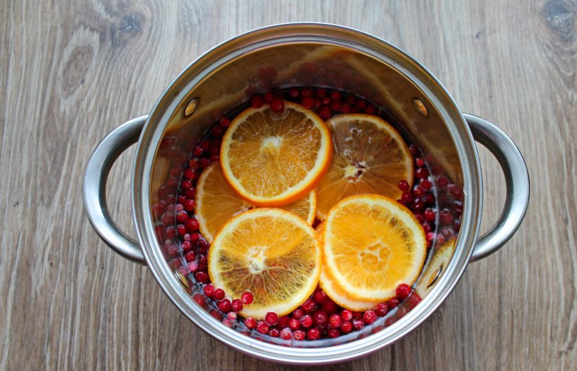 1. Этап. Брусничный глинтвейн: Апельсин нарежьте колесиками и выложите в кастрюлю с ягодами и лимоном.