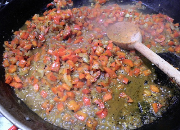 1. Этап. Черная паэлья: 4. Следующим этапом нужно обжарить овощи. Луковицу очистить нарезать кубиками, отправить на сковороду вместе с очищенным и измельченным перцем. Посолить слегка и поперчить по вкусу. Обжарить немного, а затем добавить на сковороду вино.