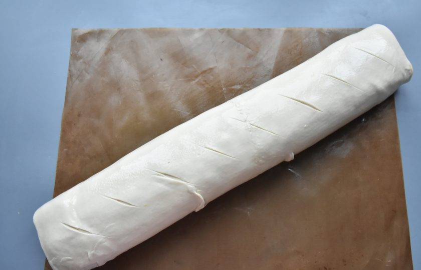 1. Этап. Штрудель с яблоками и брусникой: Используя силиконовый коврик, на котором раскатали тесто, сверните рулет. Закрепите рулет с краев и выложите его швом вниз. Сворачивайте рулет очень аккуратно, так как тесто достаточно тонкое и может порваться.