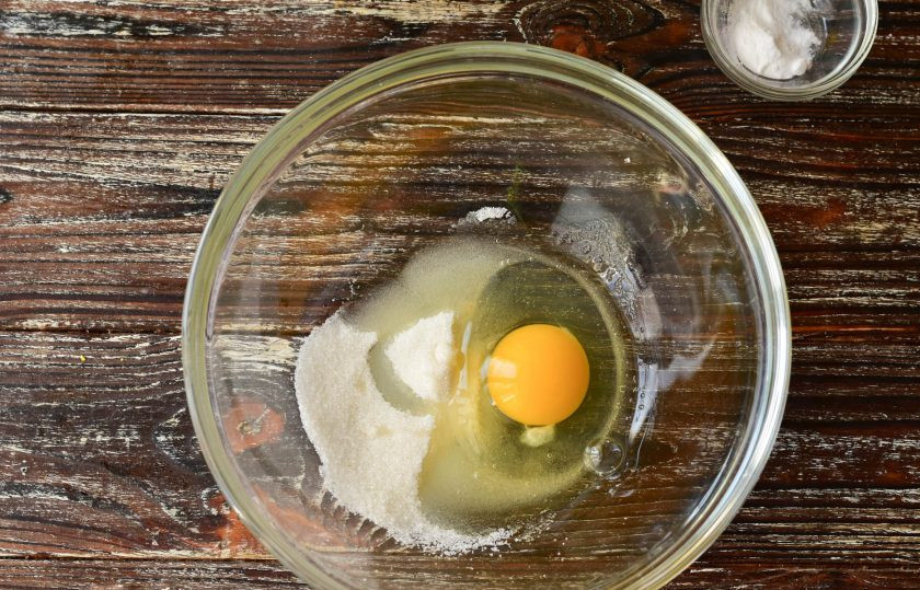 1. Этап. Толстые блины на соде: В миску вбейте куриное яйцо. Всыпьте сахар.