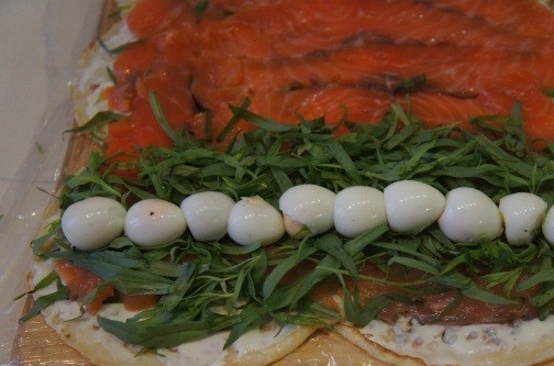 1. Этап. Рулеты из блинов с семгой: С той стороны блинного полотна, где рыба выложена с самого края, выкладываем полосу зелени, а посередине выкладываем яйца.