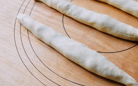 1. Этап. Рецепт сосисок в тесте: 1. В чашу комбайна добавьте сливки, молоко, 1 яйцо, сахар, муку, дрожжи, соль. Замесите тесто в течение 15 минут, затем переложите его в миску, смазанную растительным маслом, и накройте полотенцем. Через 1,5-2 часа тесто хорошо поднялось. Разделите тесто на 12 частей и скатайте их в тонкие колбаски.