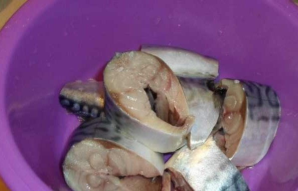 1. Этап. Скумбрия, тушенная в сметане: Скумбрию промойте, почистите и выпотрошите, удалите у неё голову. Нарежьте рыбу на порционные куски, уложите их в миску. Посолите, поперчите, перемешайте и оставьте.