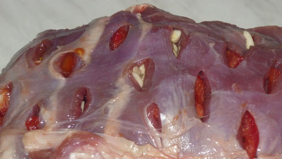 1. Этап. Баранина с помидорами в фольге: 2. А теперь делаем в мясе надрезы, и фаршируем баранину по всему периметру чесноком и помидорками. Обсыпаем солью и специями.