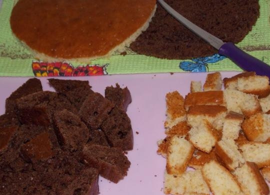 1. Этап. Ванька кучерявый: Остужаем бисквиты, обрезаем около 1/4 коржей по краям, формируя круг или квадрат. Обрезки режем примерно одинаковыми кубиками.