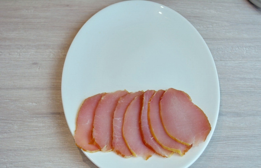 1. Этап. Мясная нарезка в виде ёлочки: На широкое белое блюдо выложите более крупные из имеющихся кусочков. У меня это балык. Это будет нижний слой елочки.