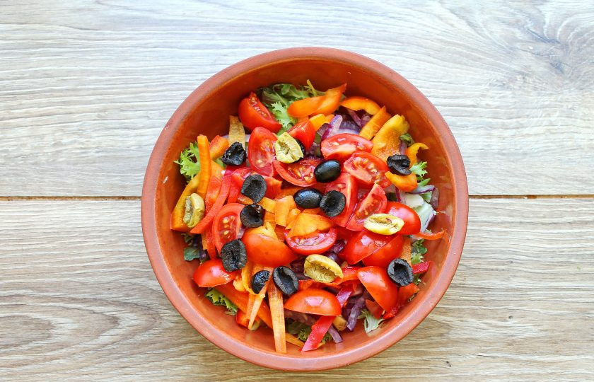 1. Этап. Салат с жареным тунцом: Маслины порежьте и добавьте в миску с овощами.