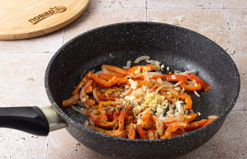 1. Этап. Карри с фасолью: Добавьте порезанный соломкой сладкий перец и готовьте еще 2-3 минуты. Затем добавьте мелко порубленный чеснок и корень имбиря. Приправьте все тмином, порошком карри, чили и молотым кориандром.