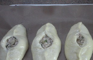 1. Этап. Расстегаи с индейкой: Подошедшее тесто разделить на 10 кусочков. Каждый раскатать в овальную лепешку, в середину выложить по полной столовой ложке начинки и придать характерную для расстегаев форму лодочки с отверстием. Оставьте готовые изделия для подъема, пока разогревается духовка до 200С.