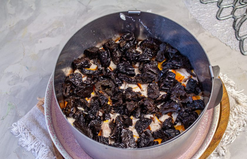 1. Этап. Салат с копченой курицей, черносливом и грецкими орехами: На курицу выложите нарезанный чернослив.