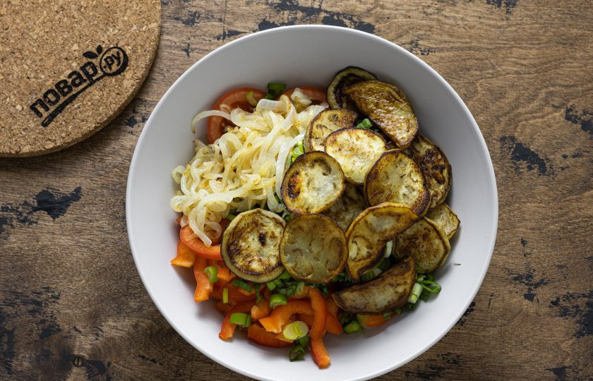 1. Этап. Салат Бакинский с баклажанами: В большой миске соедините зелень, чеснок, помидоры и сладкий перец. Добавьте лимонный сок, соль и молотый душистый перец. Затем добавьте обжаренный лук и баклажаны. Аккуратно перемешайте.