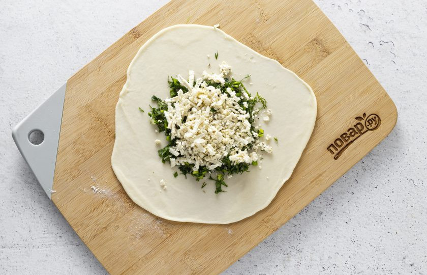 1. Этап. Лепешки с кинзой: Раскатайте тесто тонко в круглую лепешку. В центр выложите кинзу, сверху посыпьте сыром.