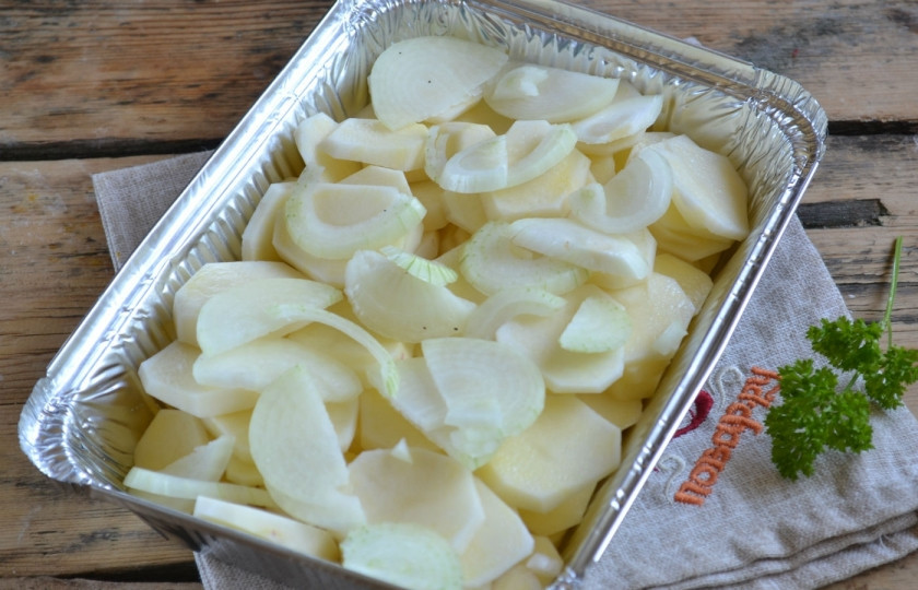 1. Этап. Картошка под соусом Бешамель: Обсушенный картофель нарежьте тоненькими кружочками. Лук разрежьте пополам и порежьте полукольцами. Форму для запекания застелите фольгой и смажьте сливочным маслом, начинайте выкладывать в неё овощи. Слой картофеля чередуйте с луком. Обязательно присаливайте, чтобы готовое блюдо не получилось пресным.