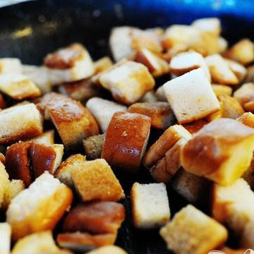 1. Этап. Салат Чизбургер: 4. Растопить 1/4 палочки сливочного масла в отдельной сковороде на слабом огне, затем добавить кубики хлеба и перемешать с маслом. Жарить гренки в сковороде на слабом огне около 10 -12 минут. Добавлять 1/4 палочки сливочного масла через каждые несколько минут, пока вы не используете все масло. Это позволит всем гренкам пропитаться маслом и сделает их вкусными.