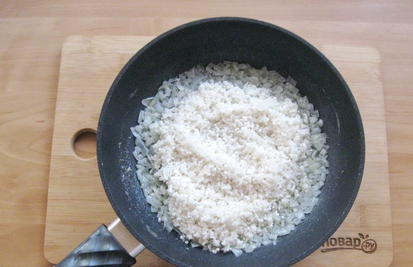 1. Этап. Ризотто по-итальянски: Добавьте к луку рис. На небольшом огне поджарьте рис в течение минуты перемешивая, чтобы рис покрылся маслом.