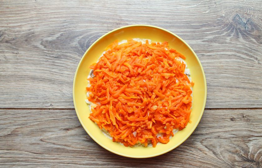 1. Этап. Селёдка под шубой с двумя видами рыбы: Морковь натрите на средней или крупной терке и выложите поверх рыбы, разровняйте и смажьте майонезом.