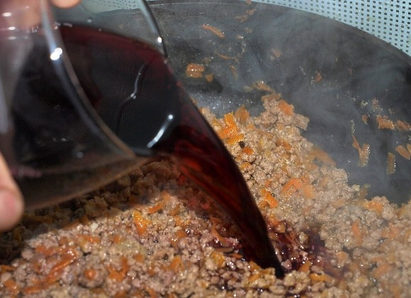 1. Этап. Соус Болоньезе: Наливаем в сковороду красное вино, перемешиваем и ждем, пока вино испарится. Время от времени перемешиваем содержимое сковороды.