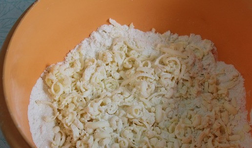 1. Этап. Яблочный пирог Хмельной: В чашу высыпать муку, сахар, разрыхлитель, перемешать. Достать масло из морозилки и натереть на терке. Удобно натирать, обмакивая масло в муку. Перемешать.