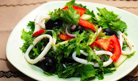 1. Этап. Вкусный салат из кальмара: Последним шагом выложите в салат кольца кальмара и оливки. Оливки можно класть целыми или порезанными колечками или напополам. Перед подачей салат слегка перемешайте и добавьте в него несколько капель оливкового масла.