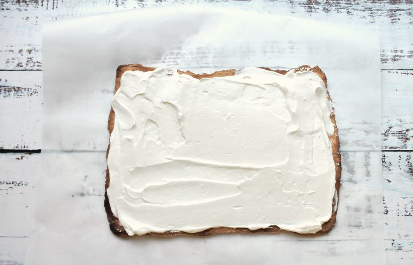 1. Этап. Меренговый рулет с мандаринами: Сливки с сахарной пудрой и ванильным сахаром взбейте в пышную массу и нанесите на корж из меренги.