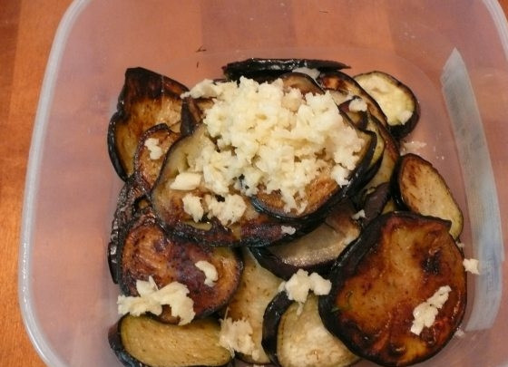 1. Этап. Быстро маринованные баклажаны: Укладываем поджаренные баклажаны в глубокую емкость и смешиваем с чесноком и солью.