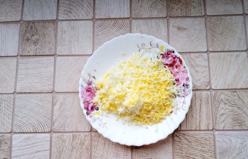 1. Этап. Слоёный салат с ананасами, курицей и жареными грибами: Яйца отварите вкрутую. Остудите, очистите и натрите на тёрке.